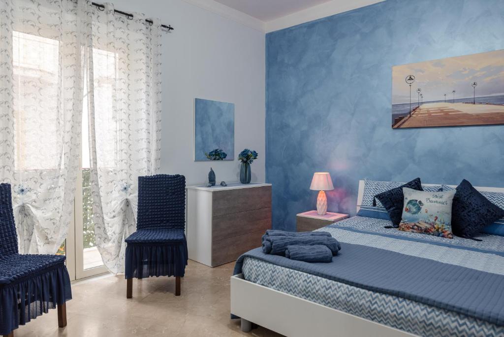 - une chambre bleue avec un lit et deux chaises dans l'établissement Appartamento Le Rondini, à Siculiana