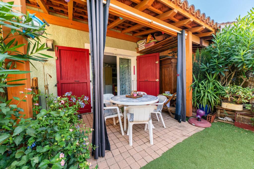 a patio with a table and chairs under a pergola at Maison Marina au Bacarès in Le Barcarès