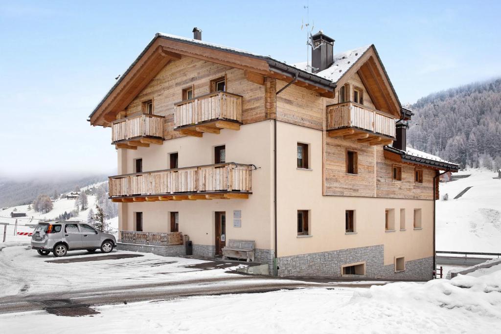 una casa con balconi in legno sul lato in cui si trova nella neve di Casa Nicoletta inverno a Livigno