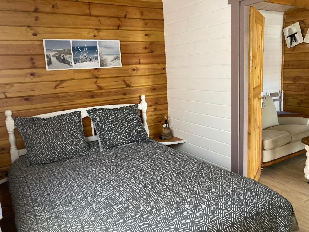 1 dormitorio con 1 cama y pared de madera en Chalet en Le Teich