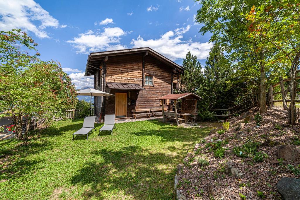 a log cabin with two benches in the yard at Bergchalet Refugium Martius in Marlengo