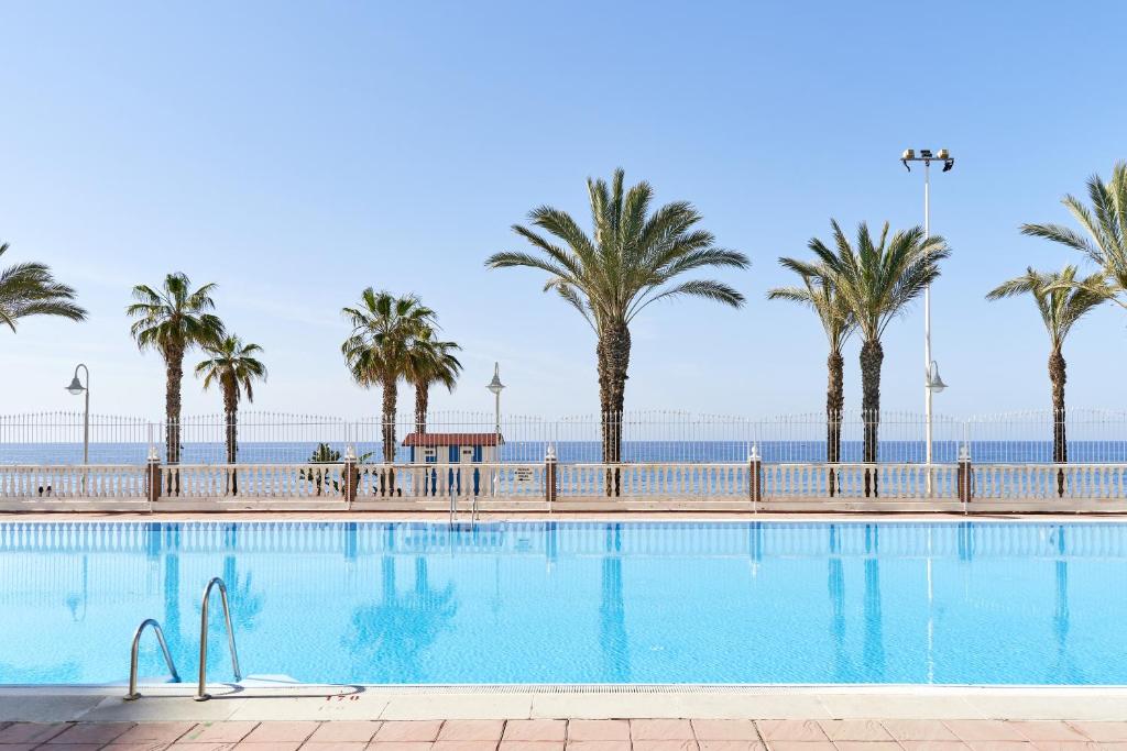 una piscina con palmeras y el océano en el fondo en Apartment in Algarrobo Costa en Algarrobo-Costa