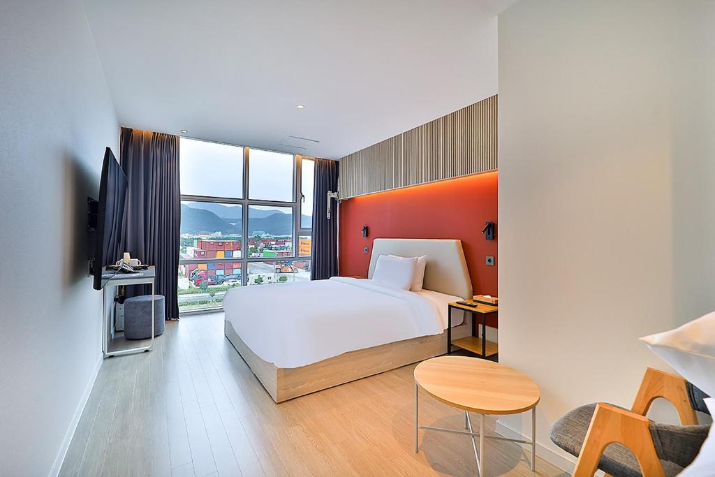 YongjaeにあるBrowndot Signature Hotelのベッドと大きな窓が備わるホテルルームです。
