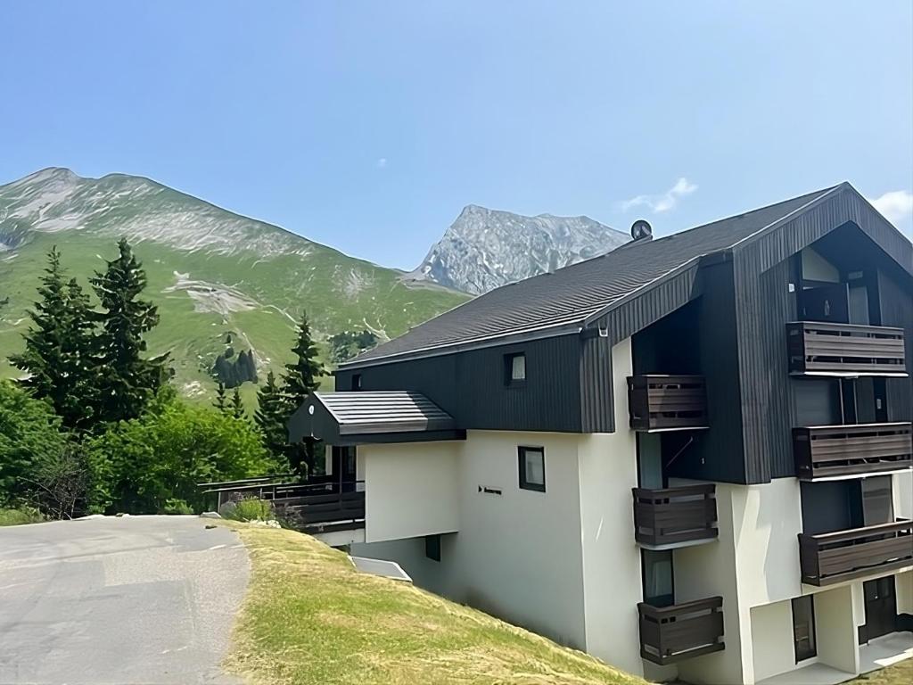 un bâtiment sur une colline avec des montagnes en arrière-plan dans l'établissement Appartement Manigod/La clusaz, à Manigod