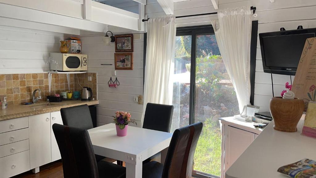 uma cozinha com uma mesa e cadeiras brancas e uma janela em בקתות עץ סקנדינביות במטולה em Metulla