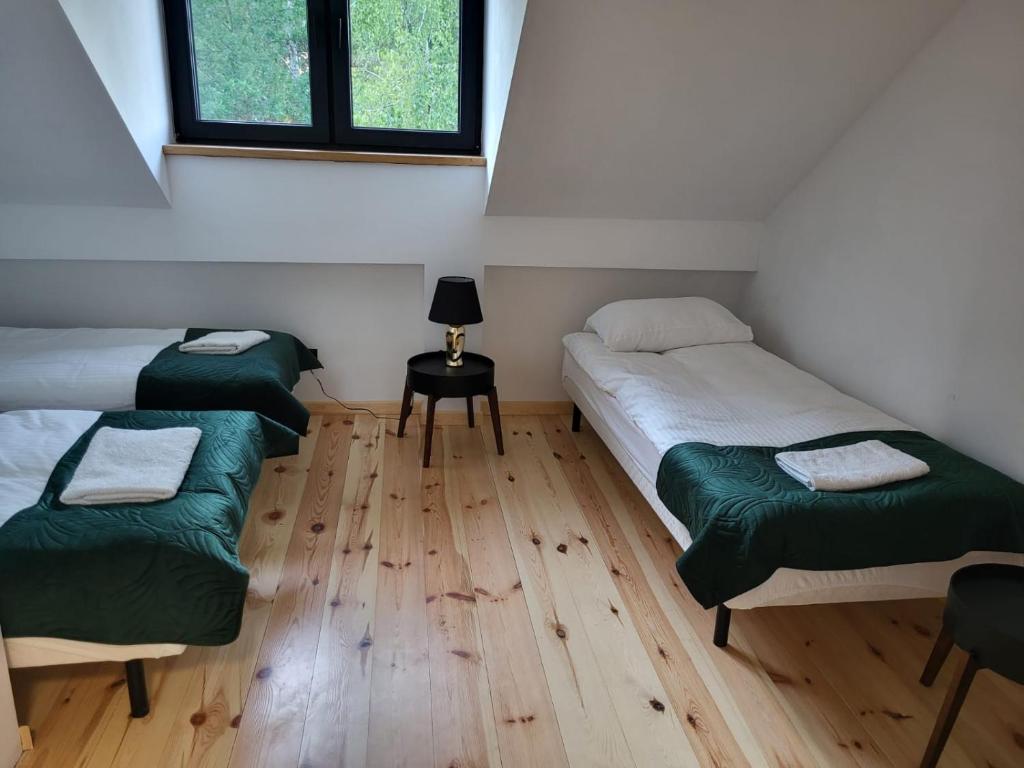 Habitación con 2 camas y mesa con lámpara. en Osada Natura Wygranka, en Kłoczew