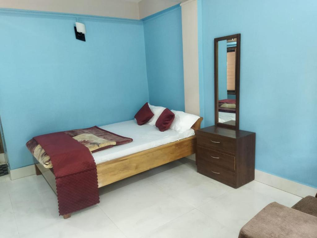 1 dormitorio con 1 cama con pared azul en Hotel Nambrog en Bomdila