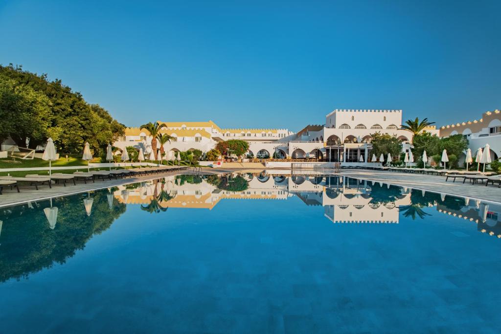 ein großer Wasserpool mit Gebäuden und Palmen in der Unterkunft Platanista Hotel in Kos-Stadt