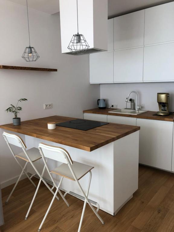 eine Küche mit weißen Schränken und einer hölzernen Arbeitsplatte in der Unterkunft Cosy apartment green&quiet Ursynów in Warschau