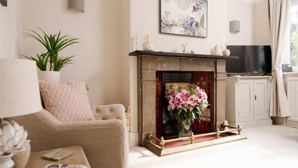 a living room with a fireplace with a vase of flowers at South View in Bakewell