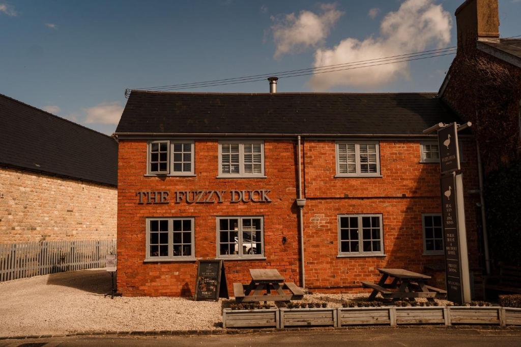 un edificio de ladrillo con una mesa de picnic delante de él en The Fuzzy Duck, en Newbold on Stour