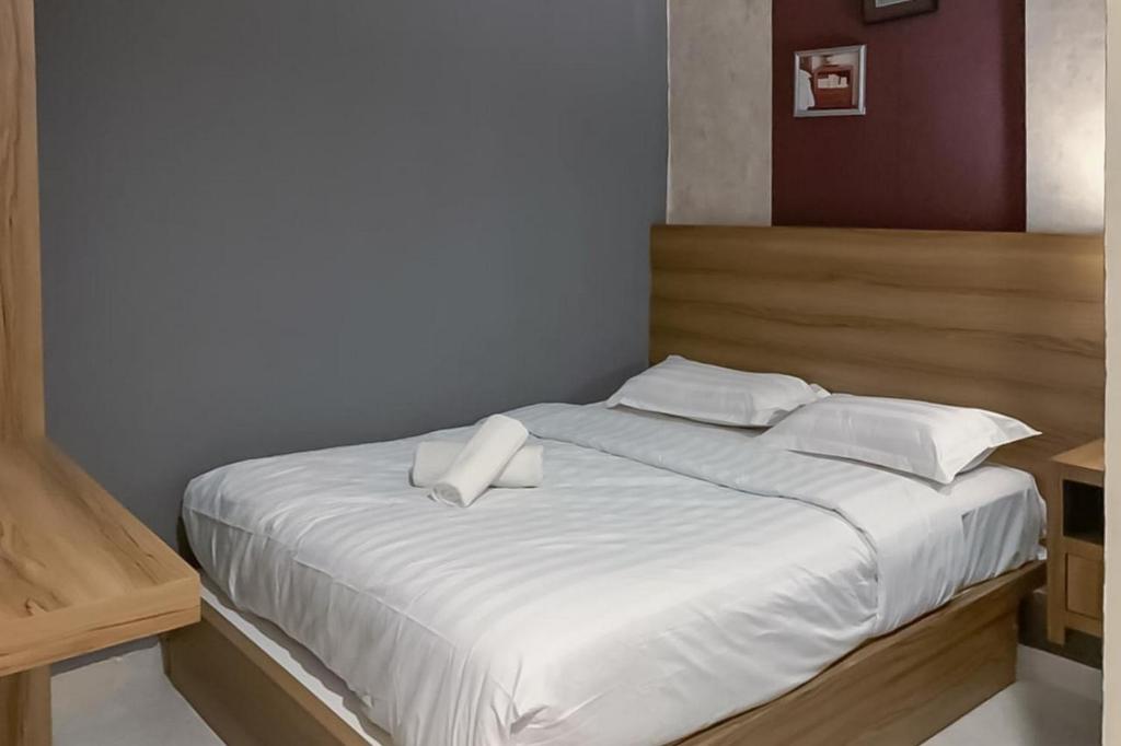 1 cama con sábanas blancas y almohadas en una habitación en RedDoorz Syariah @ Jl D I Panjaitan Batu 7 Tanjung Pinang, en Tanjung Pinang