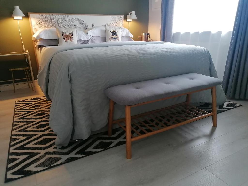 una cama con una manta y un banco al lado en No 12 B&B en Dungarvan