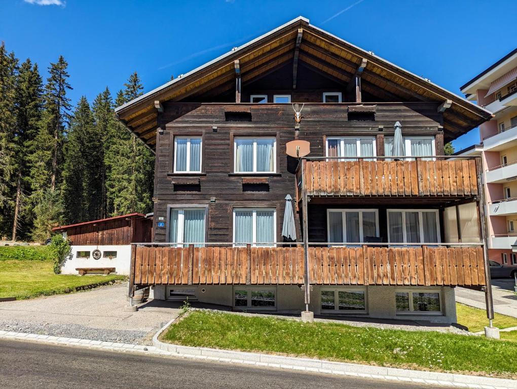 a wooden house with a balcony on a street at Chalet Schwarzsee by Arosa Holiday in Arosa