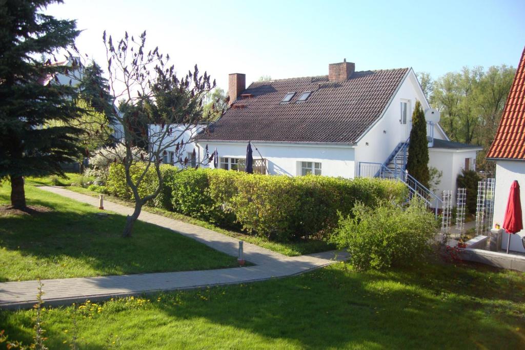 a white house with a hedge in the yard at Wolgast, FeWo Wieck in Mahlzow