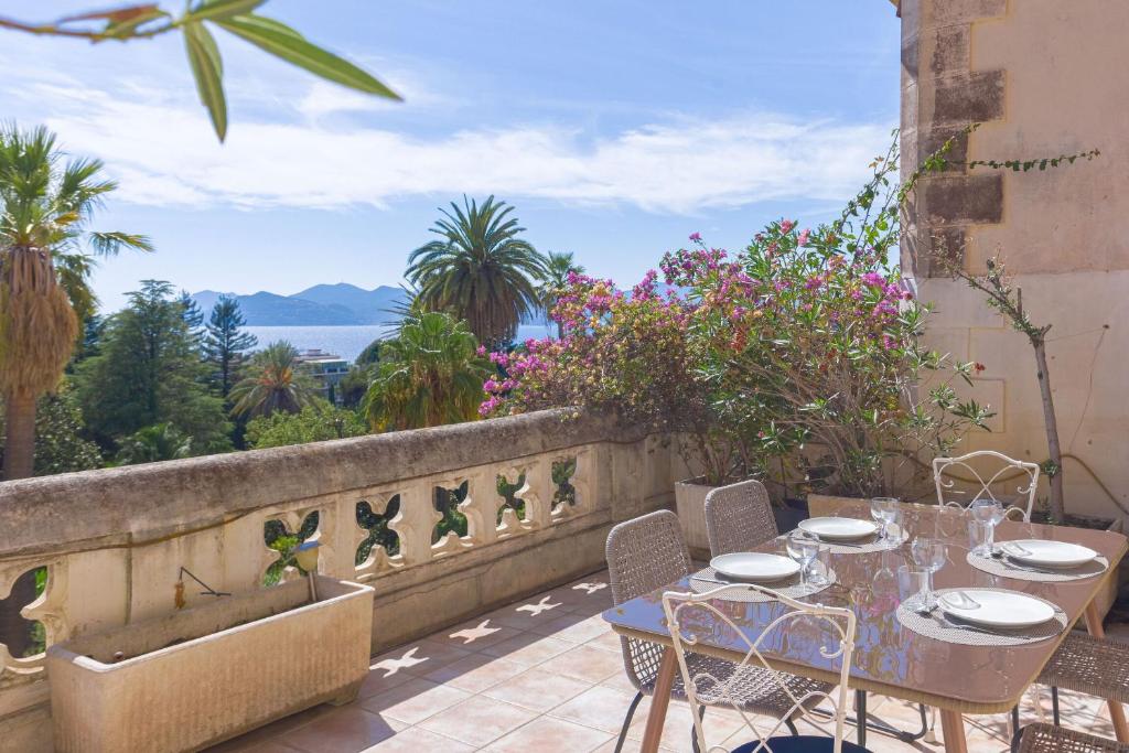 une table et des chaises sur un balcon avec vue sur l'océan dans l'établissement Le Château Vallombrosa by Halldis, à Cannes