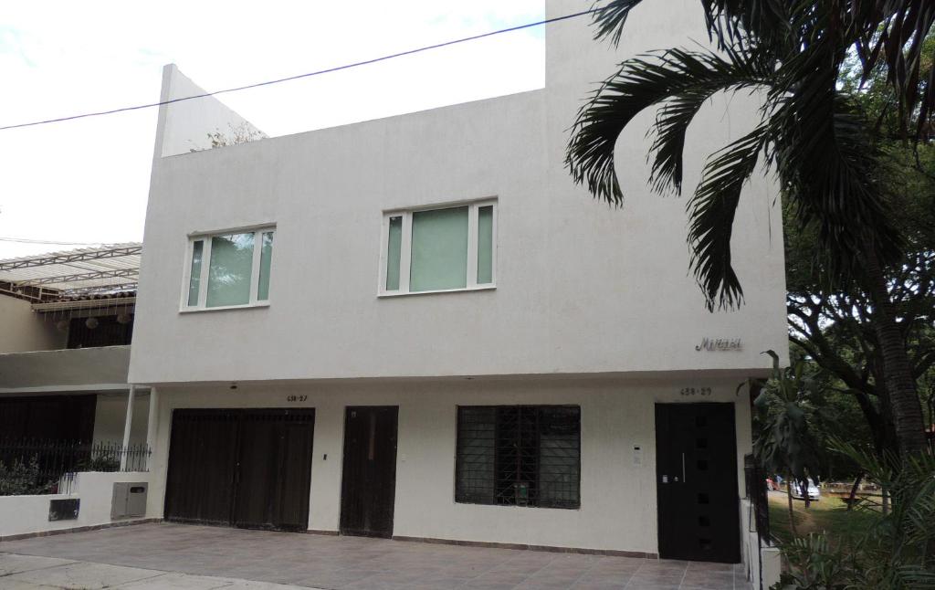 a white house with a palm tree in front of it at Meraki Host in Cali