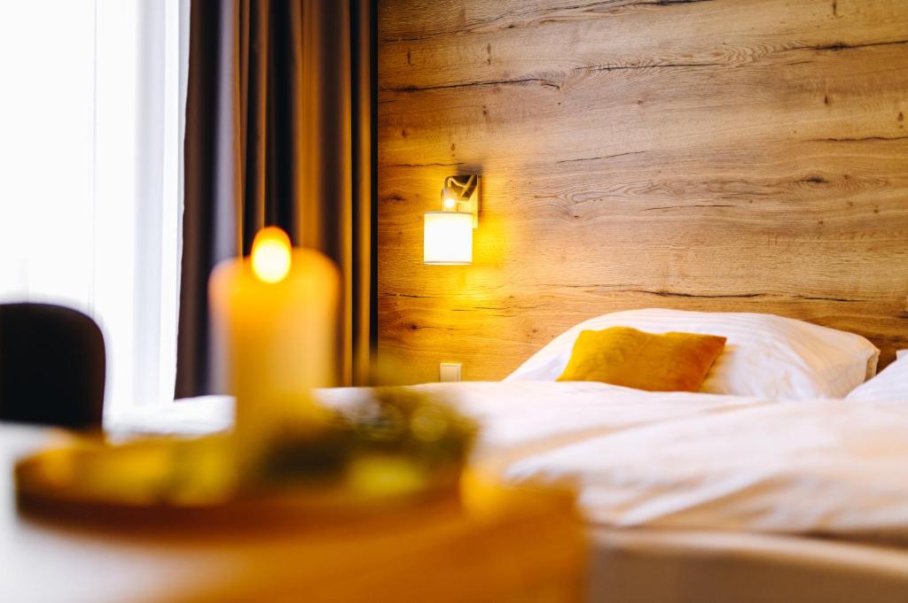 a candle sitting on a table next to a bed at Hotel SKI in Nové Město na Moravě