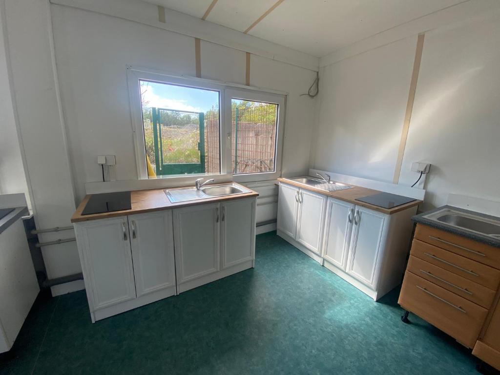 an empty kitchen with white cabinets and a window at Ubytovna SDC in Valcha