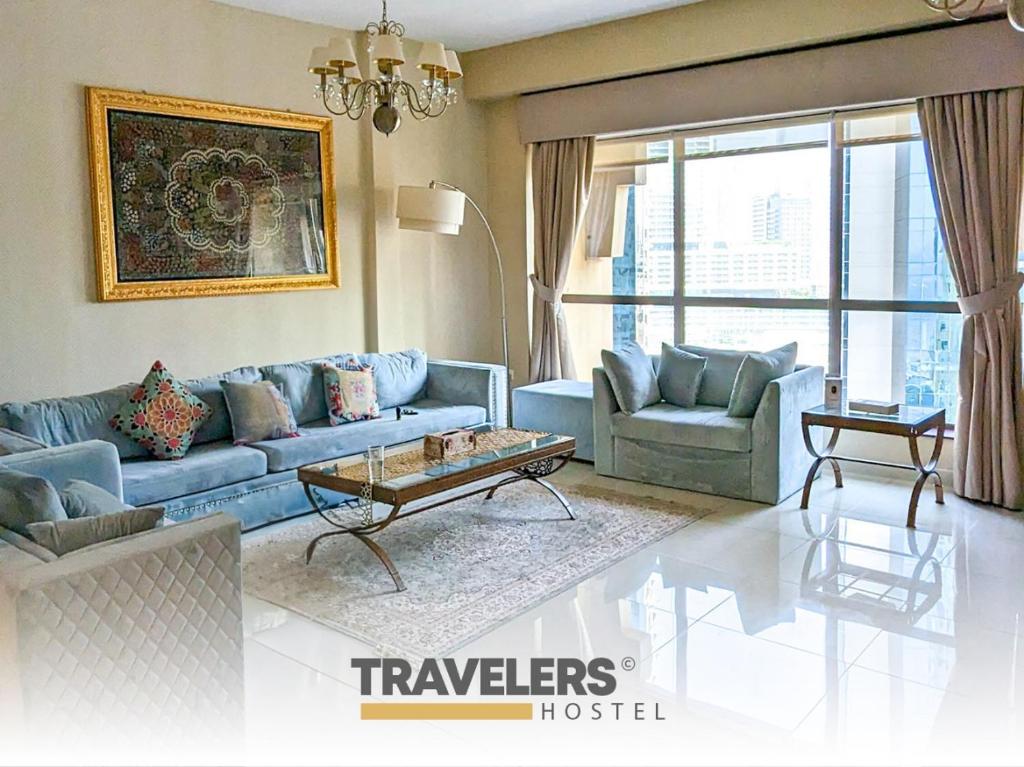 a living room with a blue couch and two chairs at Travelers - Dubai Marina Hostel in Dubai