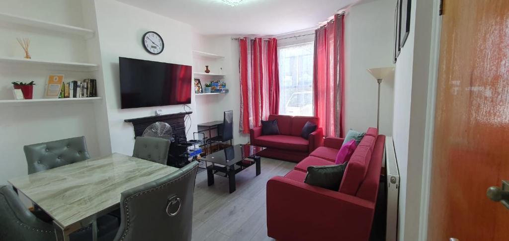 sala de estar con mesa y sala de estar con muebles de color rojo. en New Bubble Apartments, en Londres