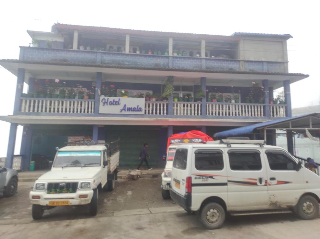 zwei weiße Fahrzeuge, die vor einem Gebäude geparkt sind in der Unterkunft Hotel Amala in Tawang