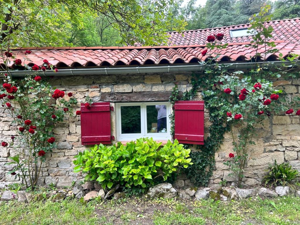 a stone house with red shutters and flowers on it at Chambre en bordure d'Aveyron in Saint-Antonin