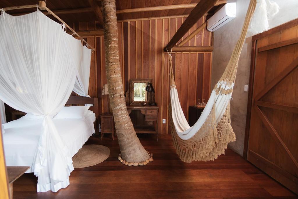 um quarto com uma cama e redes de descanso em Pousada Casa Mar pé na areia em Caraíva