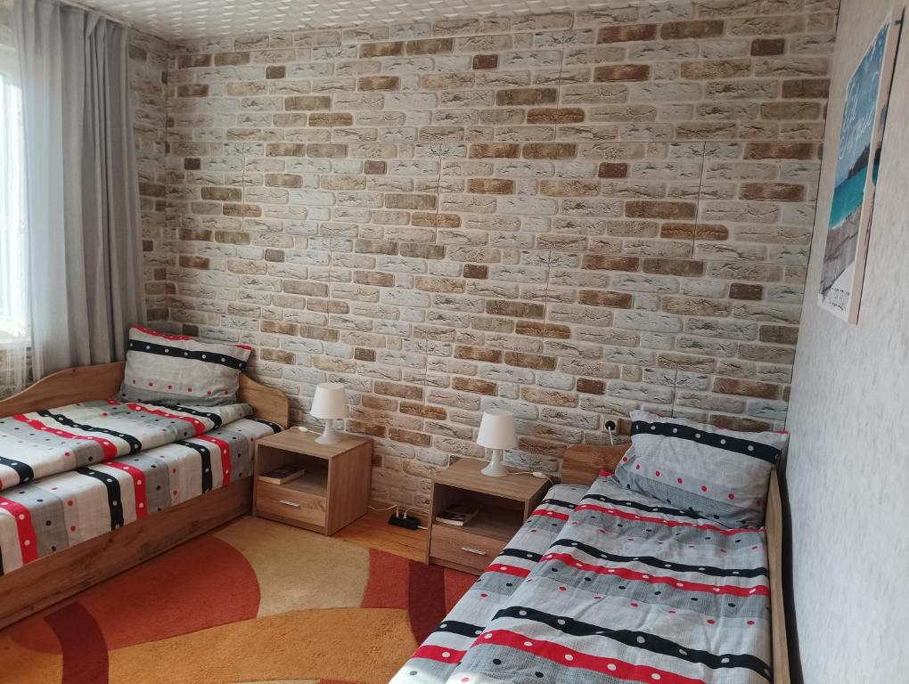 two beds in a room with a brick wall at 2-ра двойна стая in Dragoman