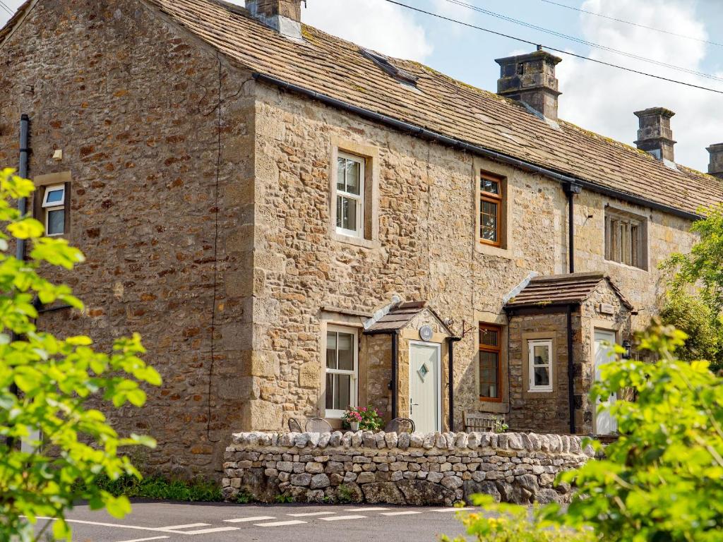 an old stone house with a stone wall at Park Grange Cottage in Skipton