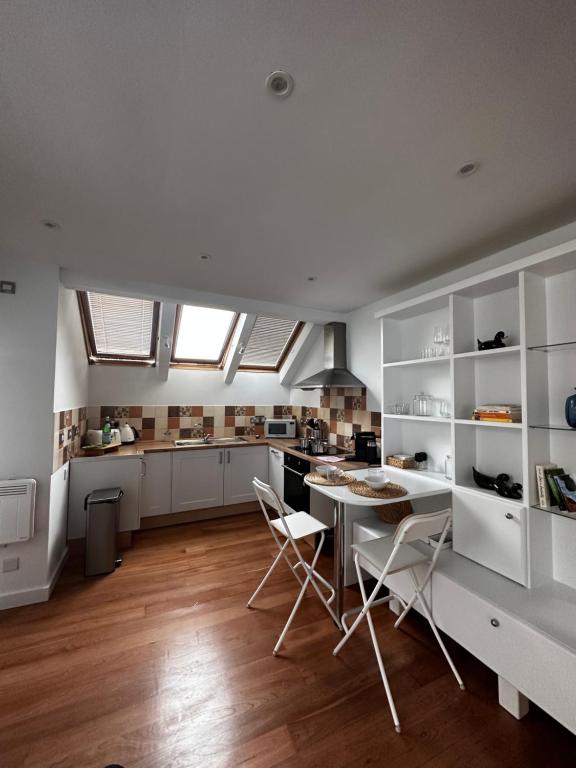 a kitchen with white cabinets and a table and chairs at Studio flat in the heart of Hampstead, London in London