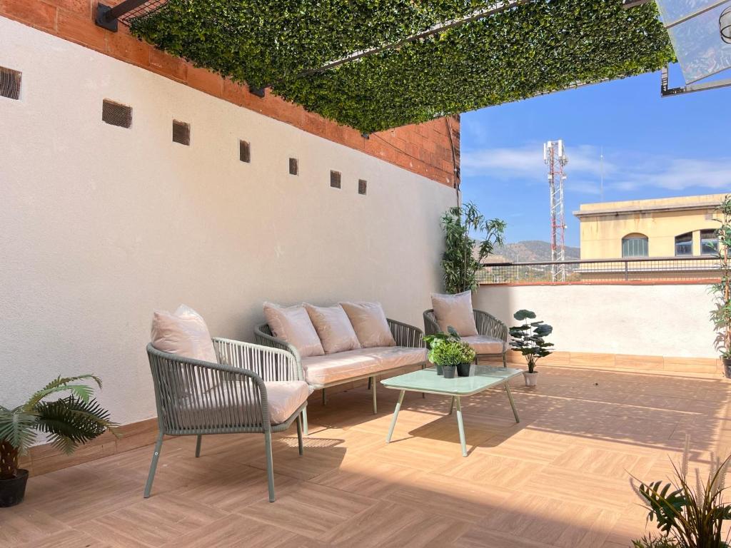 Un patio con sillas y una mesa en un tejado. en Crysoyle Apartment Barcelona Next to Camp Nou, en Hospitalet de Llobregat