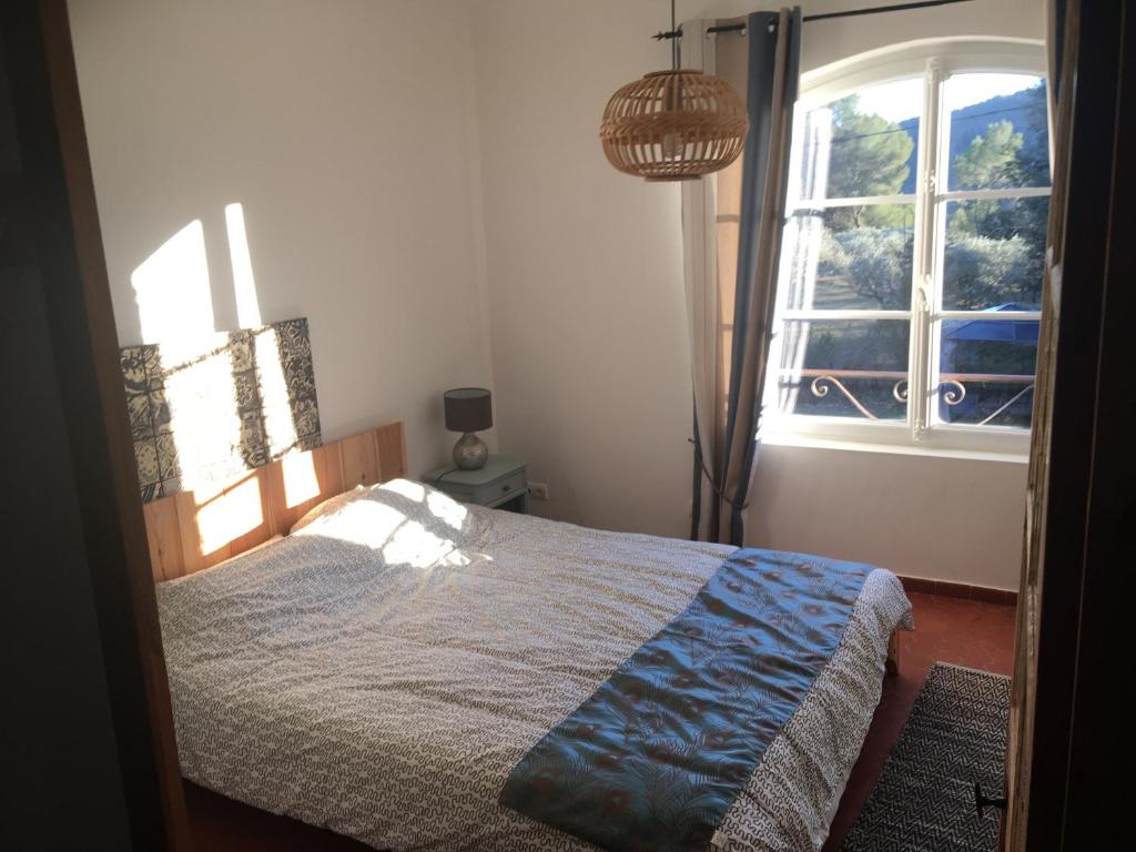 een slaapkamer met een bed voor een raam bij Mon Gîte en Provence in Salernes
