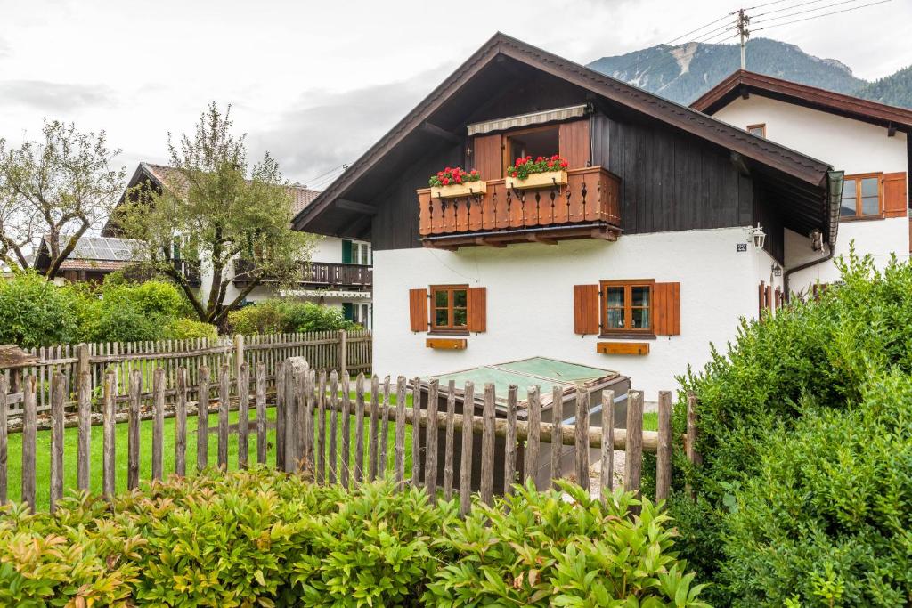 ein weißes Haus mit einem Balkon mit Blumen darauf in der Unterkunft Ferienwohnung Reschberg in Farchant