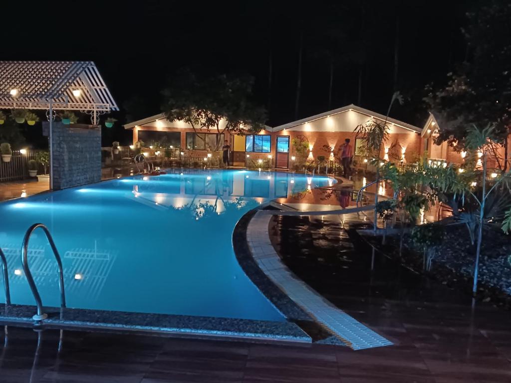 a swimming pool at night with lights on it at Vip's Ruposhi Bangla Eco Resort in Chālsa