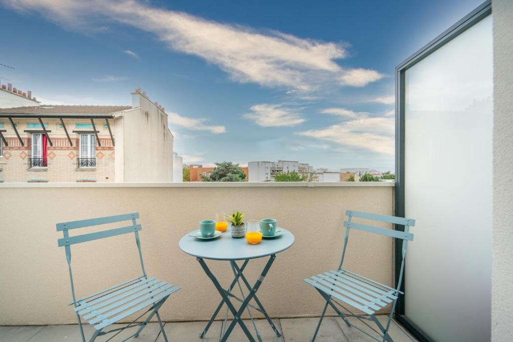 a table and two chairs on a balcony at Carré d'As - Appartement de standing in Le Bourget