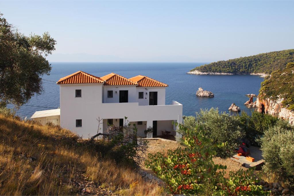 a white house on the side of a hill with the ocean at Kalithea Studios in Stafylos