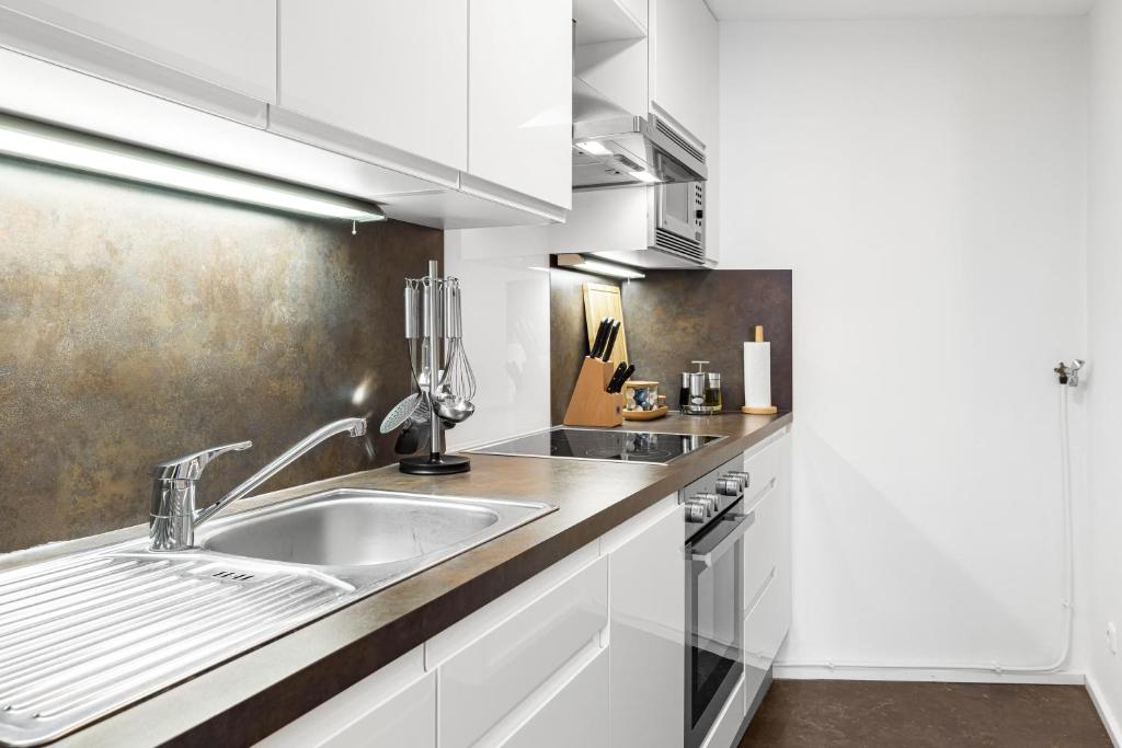 una cocina con armarios blancos y fregadero en PRIME - City Apartment für 6 - Neu & Modern, en Múnich