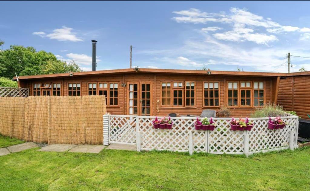una casa in legno con una recinzione di fronte ad essa di Clematis cabin a Hereford