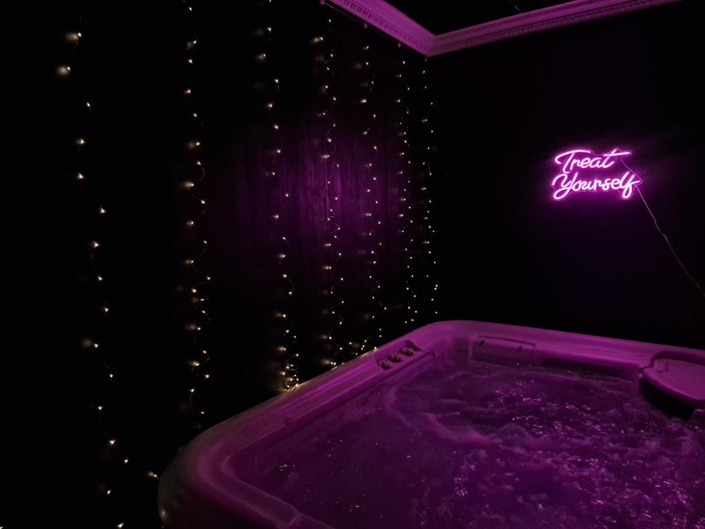 a purple bath tub in a room with a neon sign at The Penny Black Apartment With Indoor Hot Tub in Slamannan