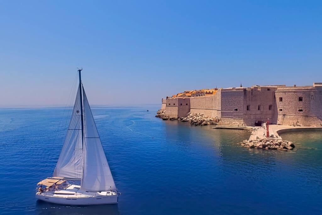 a sail boat in the water next to a castle at Dubrovnik Luxury Sailing in Dubrovnik