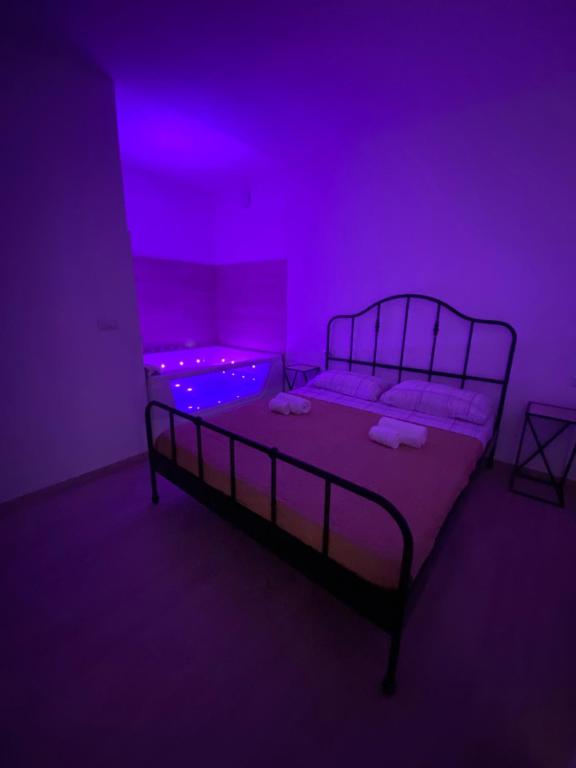 a dark room with a bed with purple lights at Maris Suite - Appartamento con vasca idromassaggio in Alghero