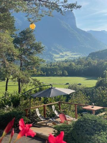 einen Tisch und Stühle mit einem Regenschirm und Blumen in der Unterkunft Chez Corinne in Alex