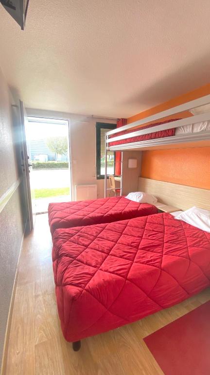 a large red bed in a room with a window at Premiere Classe Quimper in Quimper
