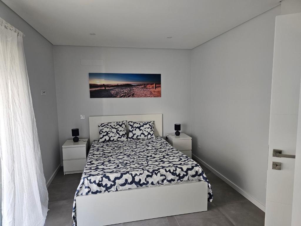 een witte slaapkamer met een bed en een schilderij aan de muur bij Apartment Dona Vitória - Monte Gordo Beach in Monte Gordo