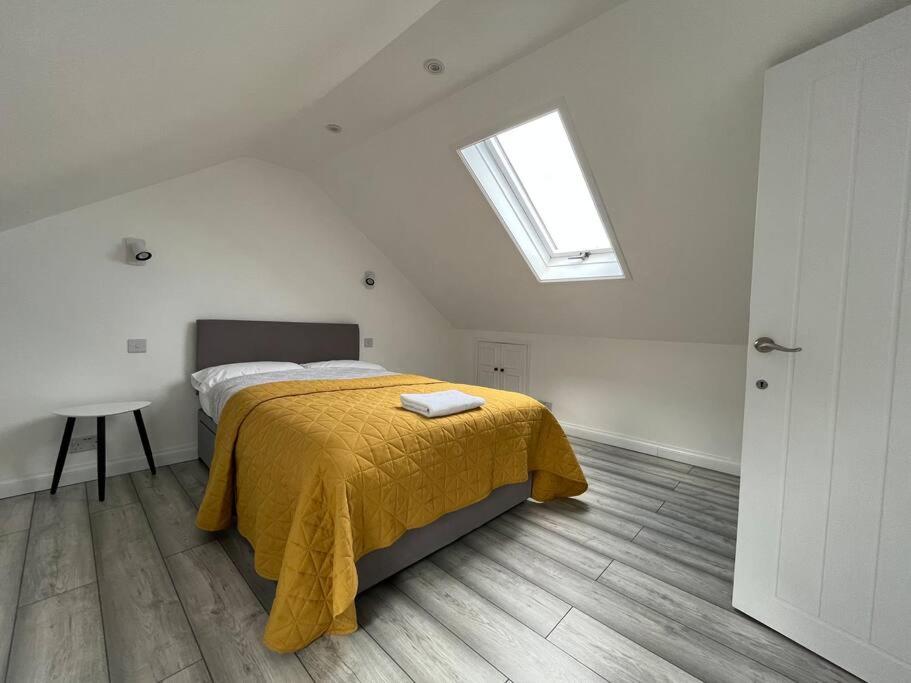 a bedroom with a bed with a yellow blanket and a skylight at Spacious Modern Flat in Mitcham in Mitcham