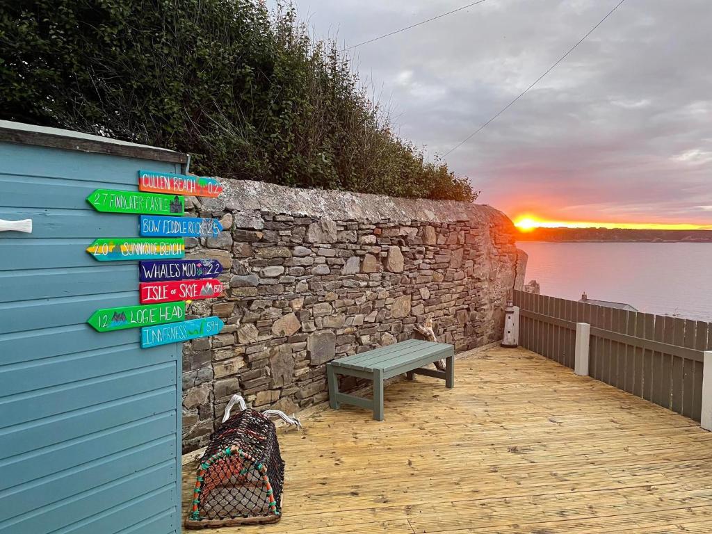 Una pared con letreros junto a un banco. en Hill Crest - cliff top cottage with stunning views, en Cullen