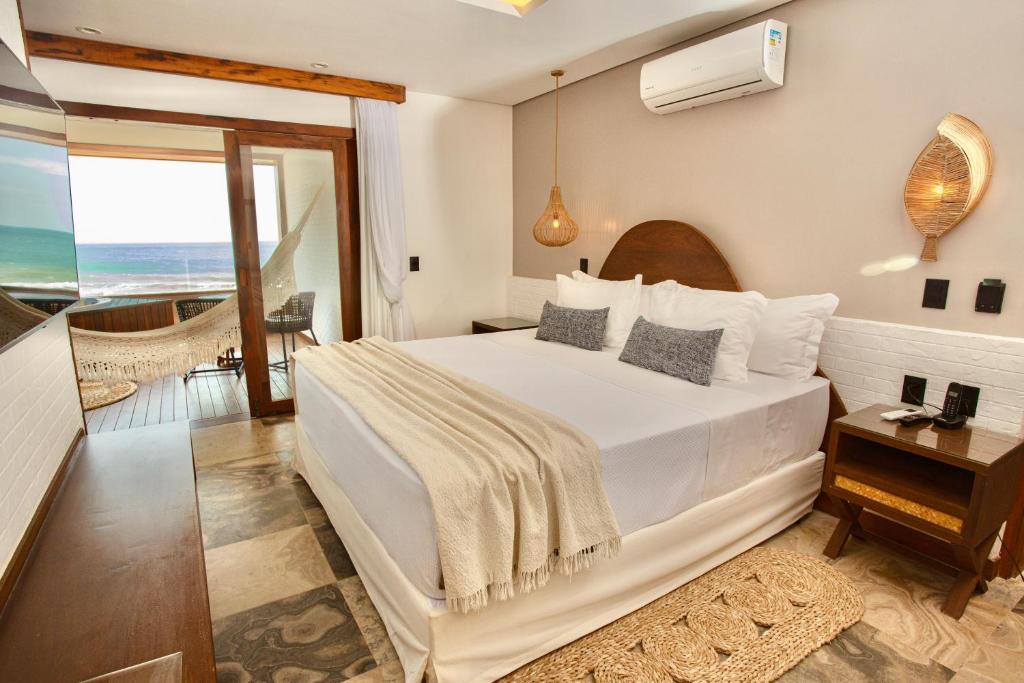 a bedroom with a large white bed and a balcony at Carlore Hotel Taíba in Taíba