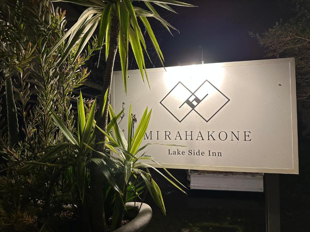 um sinal com uma planta em frente a um edifício em Lake Side Inn MIRAHAKONE em Moto-hakone