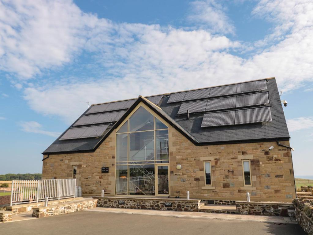 uma casa com painéis solares no telhado em St Dolmen em Embleton